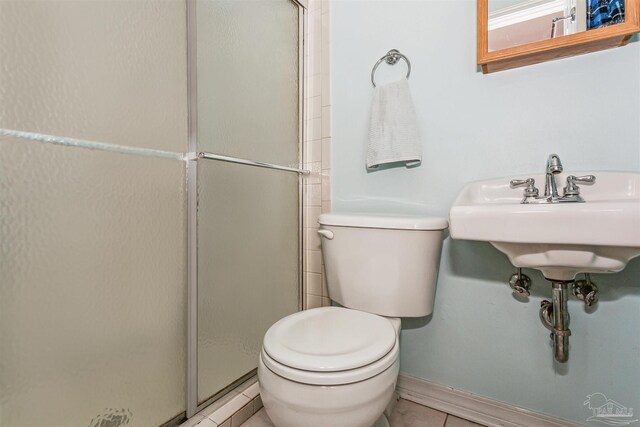 bathroom featuring tile patterned floors, baseboards, a stall shower, and toilet