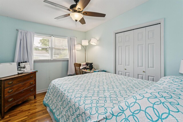 bedroom with a closet, ceiling fan, wood finished floors, and baseboards