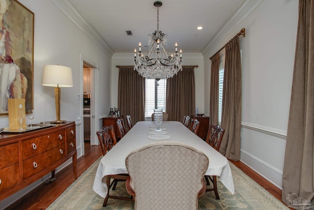 dining area featuring visible vents, baseboards, an inviting chandelier, ornamental molding, and dark wood finished floors
