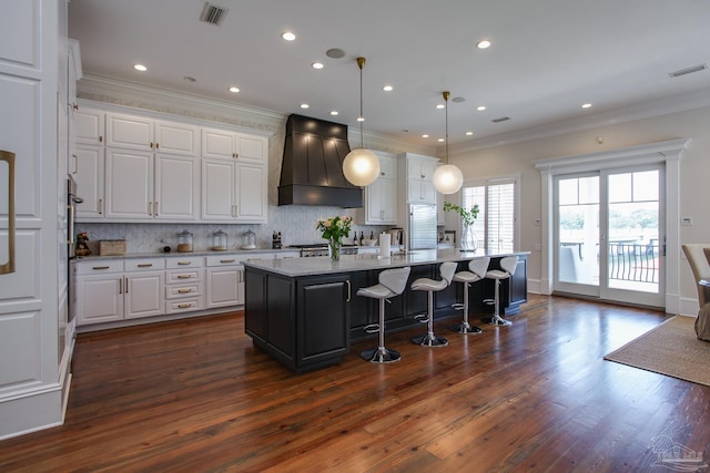 kitchen featuring decorative light fixtures, custom exhaust hood, dark hardwood / wood-style flooring, white cabinets, and a center island with sink