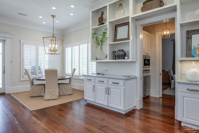 dining area with dark wood-type flooring, ornamental molding, and a notable chandelier