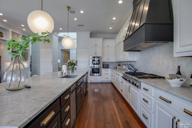 kitchen featuring custom range hood, backsplash, dark wood-type flooring, appliances with stainless steel finishes, and sink