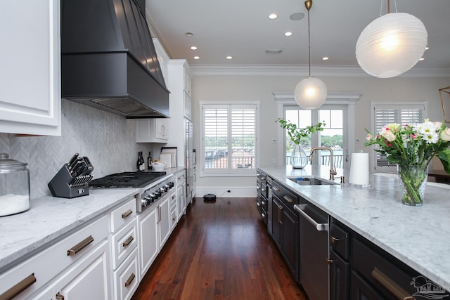 kitchen featuring tasteful backsplash, a sink, ornamental molding, appliances with stainless steel finishes, and premium range hood