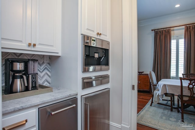 kitchen featuring tasteful backsplash, ornamental molding, dark wood-style floors, a warming drawer, and white cabinetry