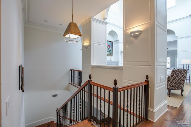 staircase with wood-type flooring and ornamental molding