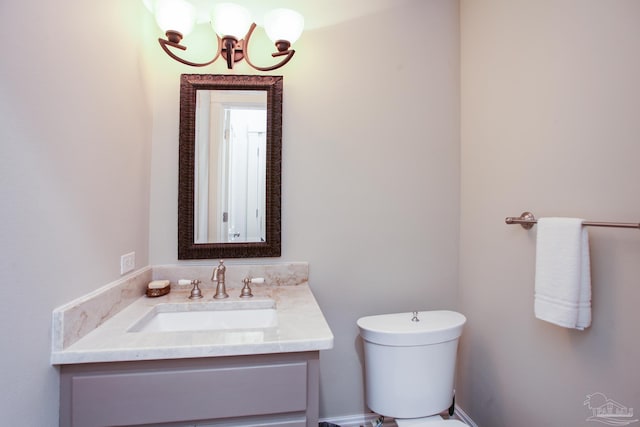 half bath with toilet, a chandelier, and vanity