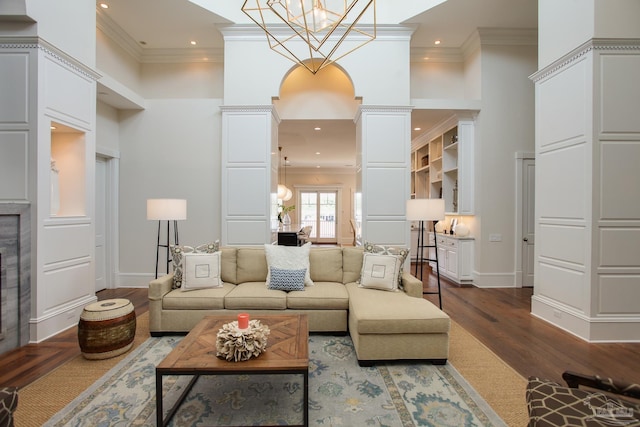 living room with ornate columns, wood-type flooring, crown molding, and a chandelier