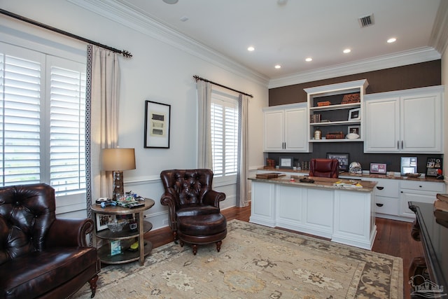interior space with visible vents, built in desk, crown molding, white cabinetry, and wood finished floors