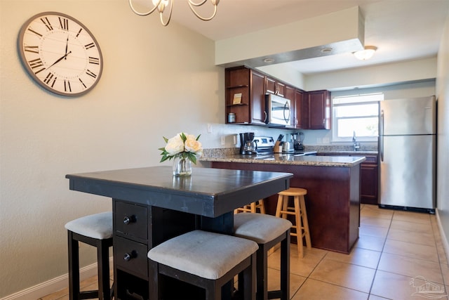 kitchen with stainless steel appliances, a kitchen island, a breakfast bar area, and light tile patterned floors