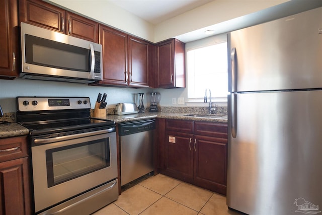 kitchen featuring dark stone countertops, appliances with stainless steel finishes, sink, and light tile patterned floors