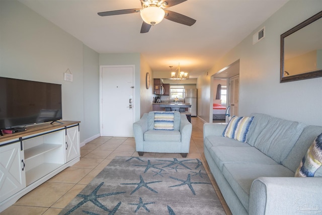 tiled living room featuring ceiling fan with notable chandelier