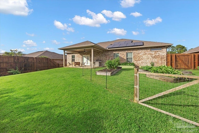 5379 Longhorn Trl, Gulf Breeze, FL 32563 - back of property with solar panels, a patio, a fenced backyard, brick siding, and a garden