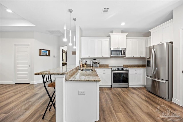 5379 Longhorn Trl, Gulf Breeze, FL 32563 - kitchen with appliances with stainless steel finishes, a peninsula, dark wood-style flooring, white cabinets, and recessed lighting