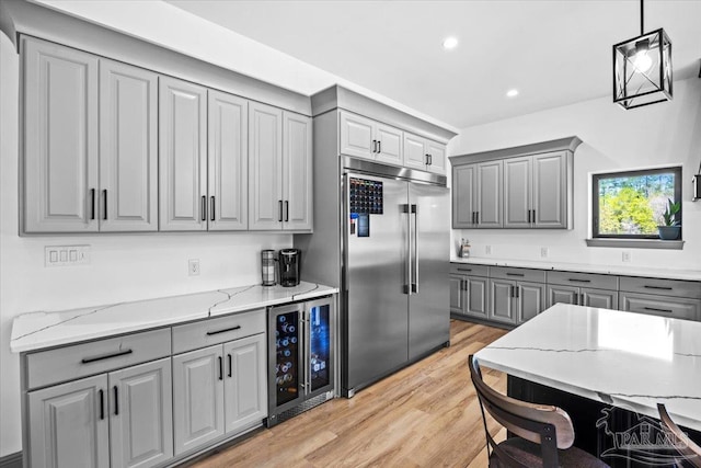 kitchen featuring light wood-style floors, recessed lighting, wine cooler, gray cabinetry, and built in fridge