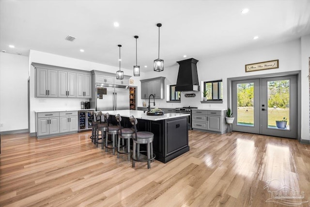 kitchen featuring custom range hood, gray cabinets, light countertops, stainless steel appliances, and beverage cooler