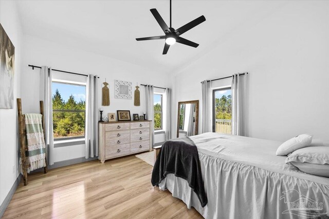 bedroom with multiple windows, vaulted ceiling, and light wood-style floors