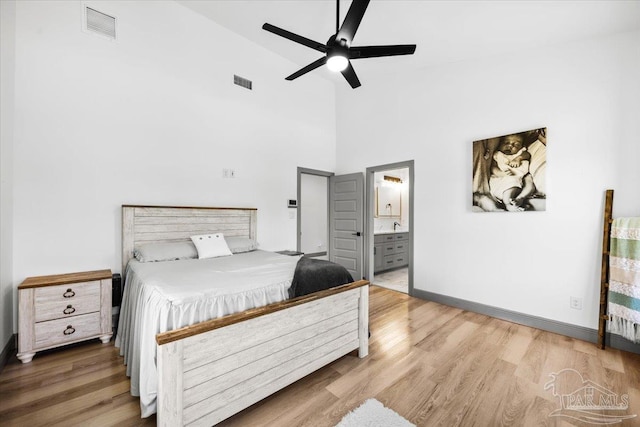 bedroom with high vaulted ceiling, visible vents, connected bathroom, and wood finished floors