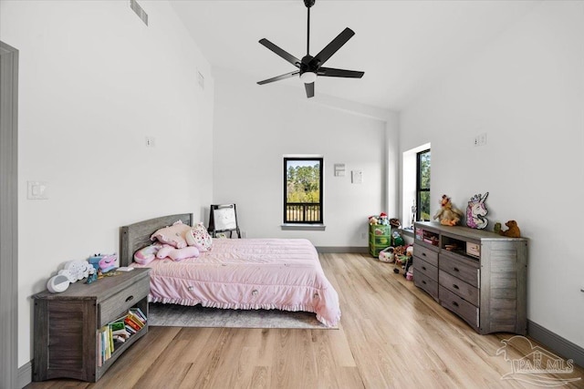 bedroom featuring visible vents, baseboards, a ceiling fan, wood finished floors, and high vaulted ceiling