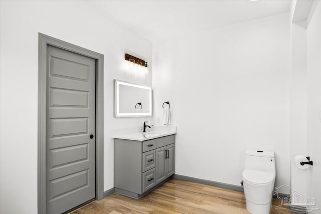bathroom featuring toilet, baseboards, vanity, and wood finished floors