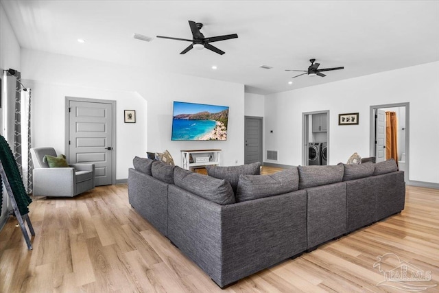 living area with separate washer and dryer, visible vents, light wood-style flooring, and ceiling fan