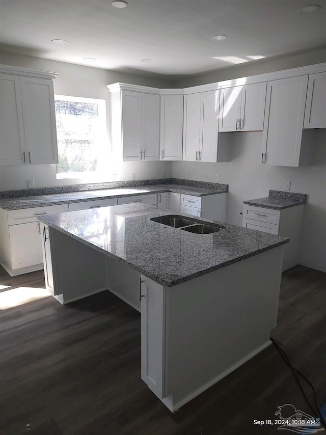 kitchen with stone counters, white cabinetry, a center island, and dark wood-type flooring