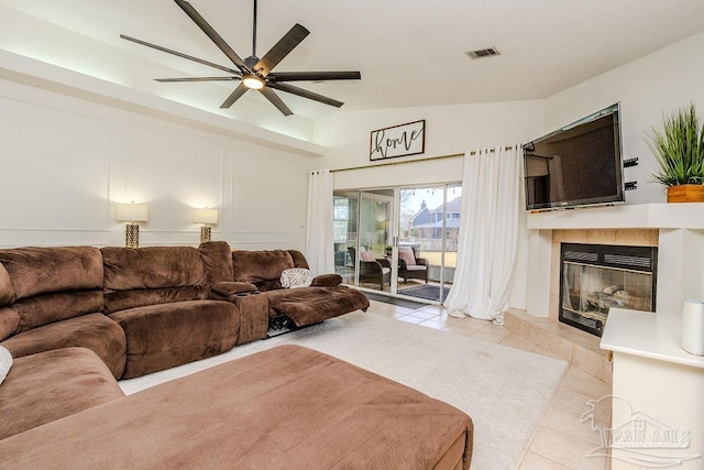 living room featuring visible vents, ceiling fan, light tile patterned flooring, and a tiled fireplace