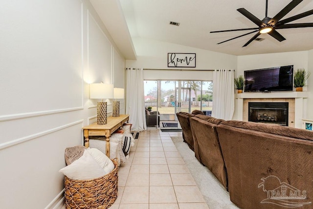 living room featuring visible vents, a ceiling fan, light tile patterned floors, vaulted ceiling, and a tile fireplace