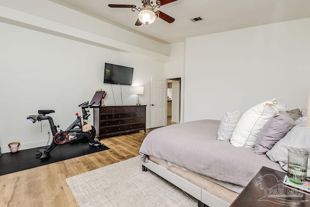 bedroom with a ceiling fan, wood finished floors, visible vents, and baseboards