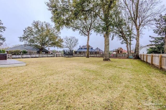 view of yard featuring a trampoline, a fenced backyard, and a patio area