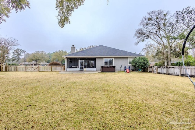 rear view of property with a lawn, a hot tub, a fenced backyard, and a sunroom