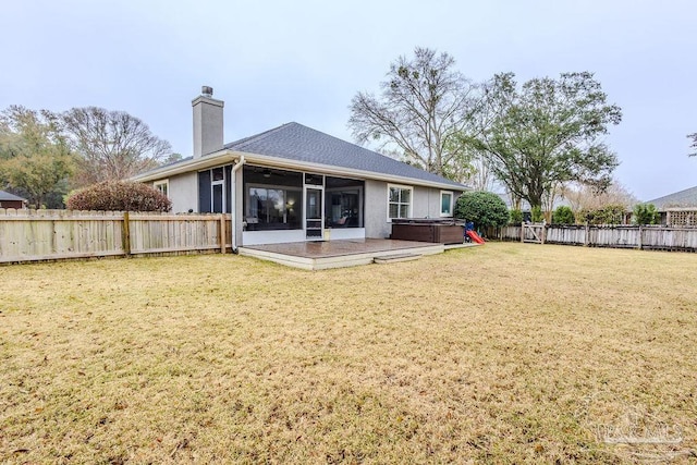 rear view of property with a hot tub, a lawn, a chimney, a fenced backyard, and a sunroom