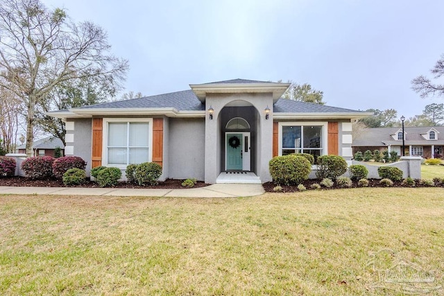 view of front of property featuring a front yard, roof with shingles, and stucco siding