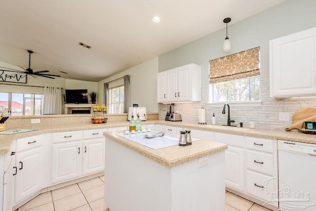 kitchen featuring a center island, dishwasher, light tile patterned floors, a ceiling fan, and a sink