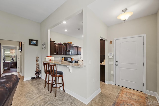 5798 Vendome Ct, Milton, FL 32583 - interior space with light stone counters, electric range oven, black microwave, a kitchen breakfast bar, and dark brown cabinets