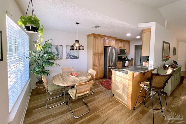 2783 Venetian Ct, Gulf Breeze, FL 32563 - kitchen with appliances with stainless steel finishes, light wood finished floors, a peninsula, a breakfast bar area, and a textured ceiling