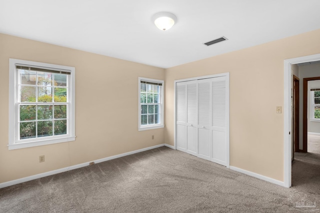 unfurnished bedroom with a closet, carpet floors, and multiple windows