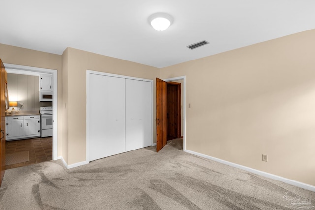 unfurnished bedroom with light carpet and a closet