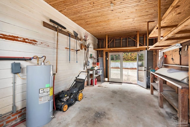 interior space featuring concrete floors, wooden ceiling, water heater, and wooden walls