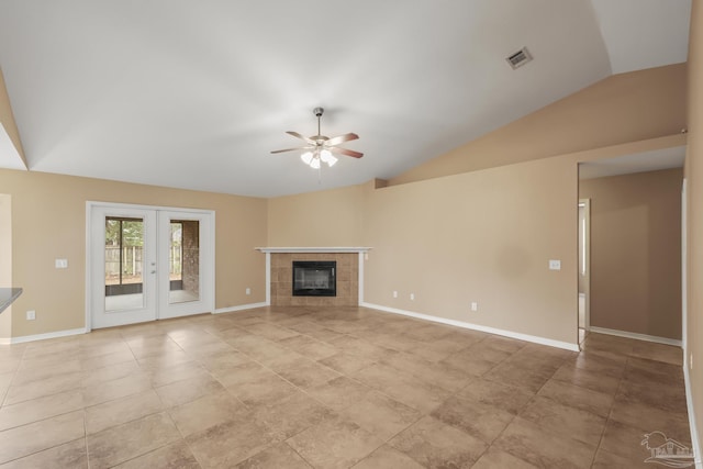 unfurnished living room with lofted ceiling, light tile patterned floors, ceiling fan, a tiled fireplace, and french doors