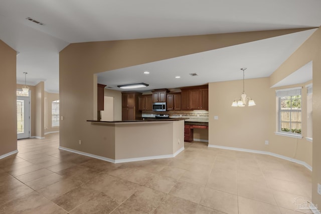 kitchen featuring a chandelier, vaulted ceiling, hanging light fixtures, light tile patterned floors, and decorative backsplash