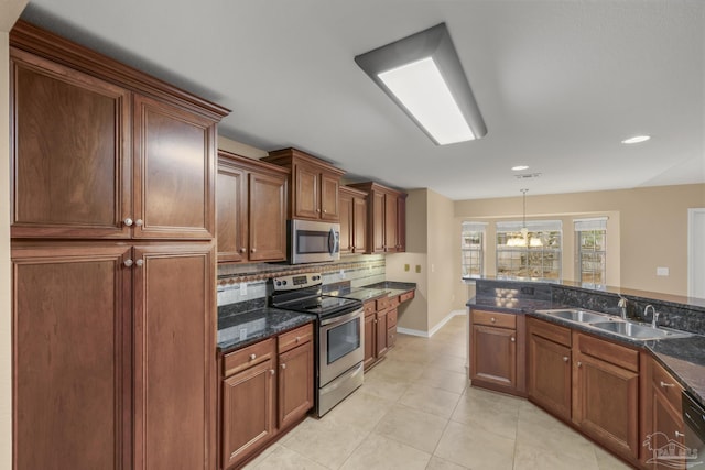 kitchen featuring appliances with stainless steel finishes, pendant lighting, sink, dark stone countertops, and backsplash