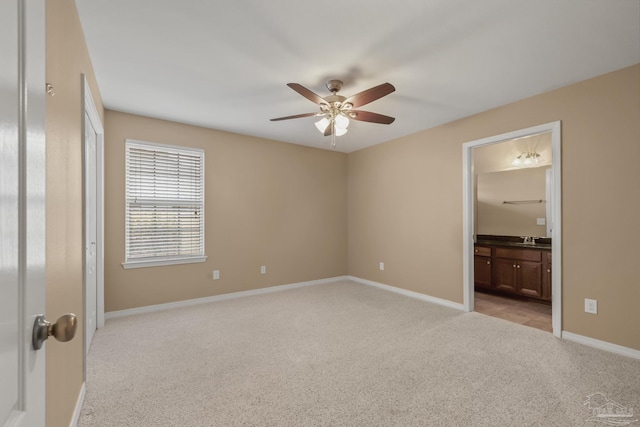 unfurnished bedroom featuring ceiling fan, sink, light carpet, and ensuite bath