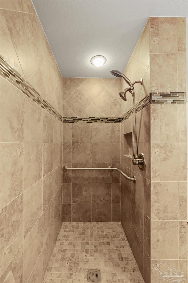 bathroom featuring tiled shower and a textured ceiling