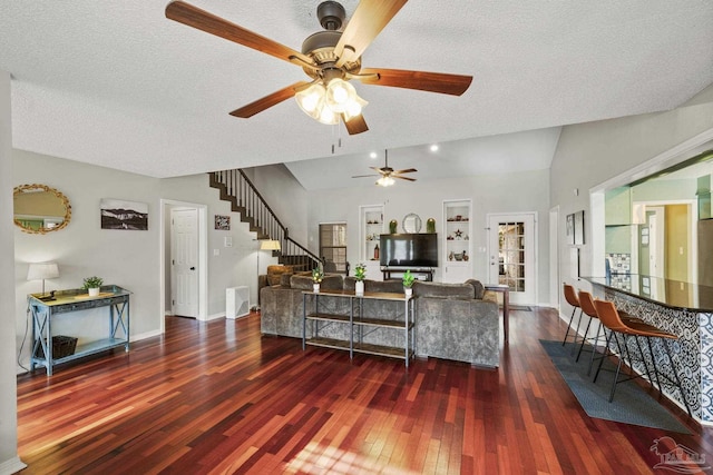 living room featuring dark wood-type flooring, lofted ceiling, and a textured ceiling