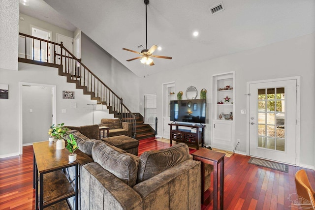 living room featuring ceiling fan, wood-type flooring, built in features, and a towering ceiling