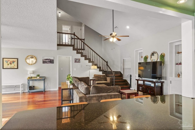 living room with a towering ceiling, wood-type flooring, and ceiling fan