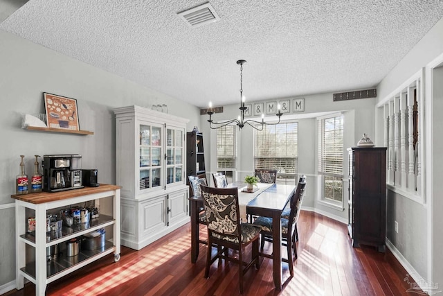 dining space with a textured ceiling, a notable chandelier, and dark hardwood / wood-style flooring