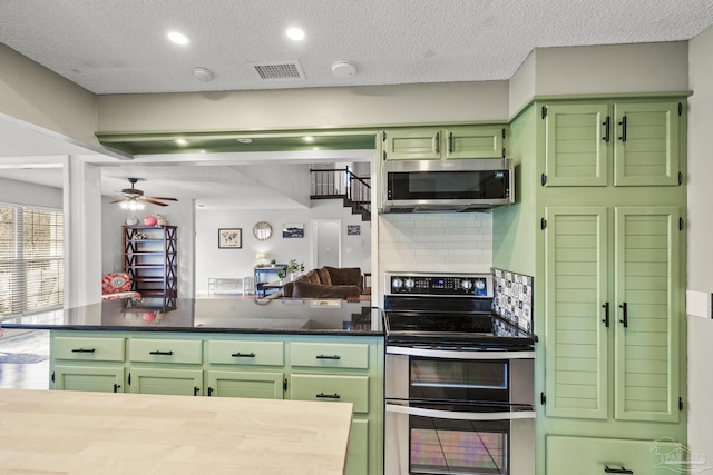 kitchen featuring ceiling fan, green cabinets, appliances with stainless steel finishes, backsplash, and kitchen peninsula