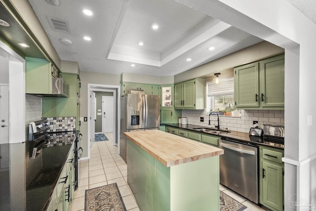 kitchen with butcher block counters, sink, appliances with stainless steel finishes, a raised ceiling, and green cabinets