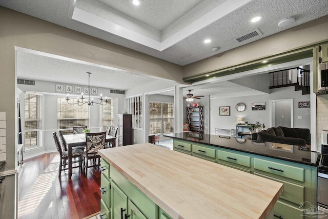 kitchen with dark wood-type flooring, wooden counters, green cabinets, a textured ceiling, and decorative light fixtures